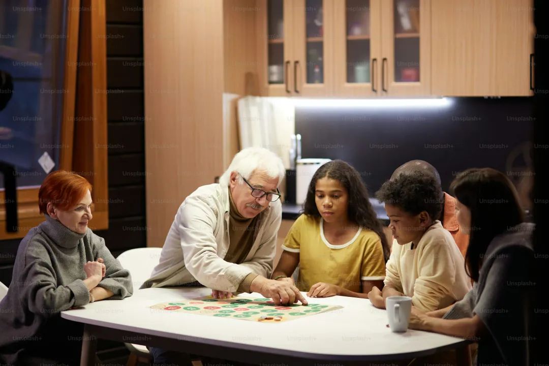 Big family sitting at the table in the domestic kitchen and playing board games together